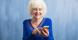 Senior lady in blue using a smartphone
