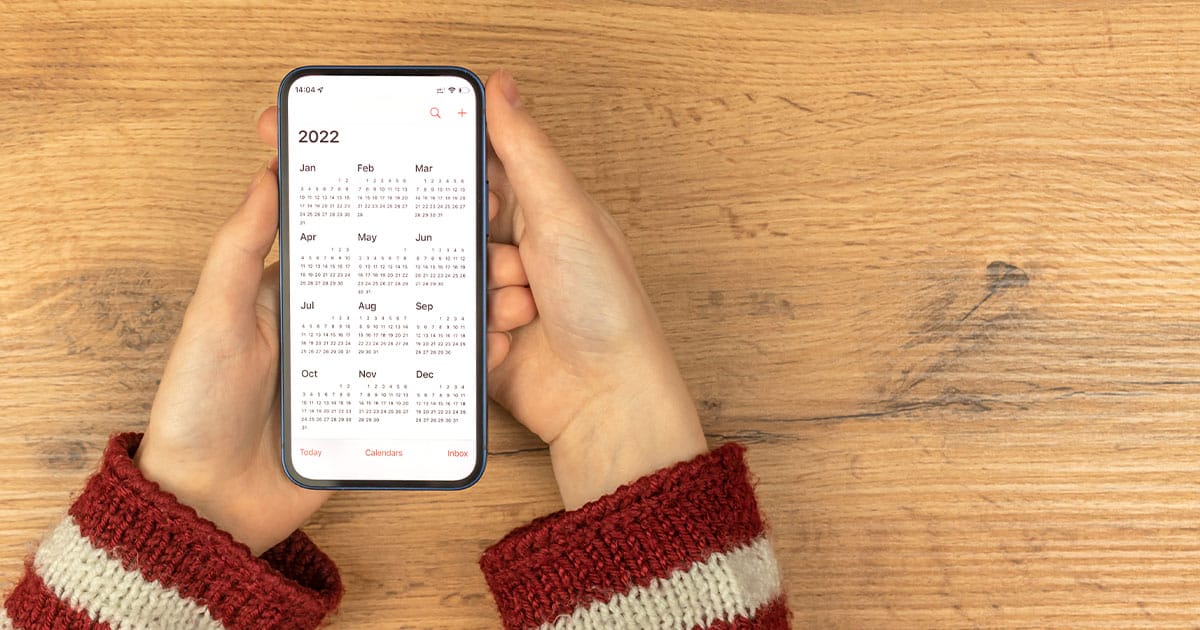 Hands holding mobile phone showing 2022 calendar