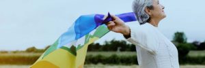 Senior lady holds lgbt flag in field